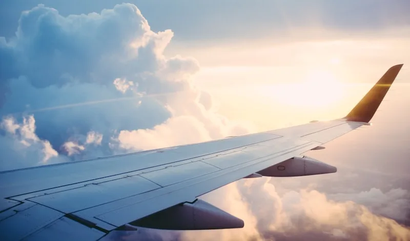 Flugzeugflügel über den Wolken bei Sonnenuntergang